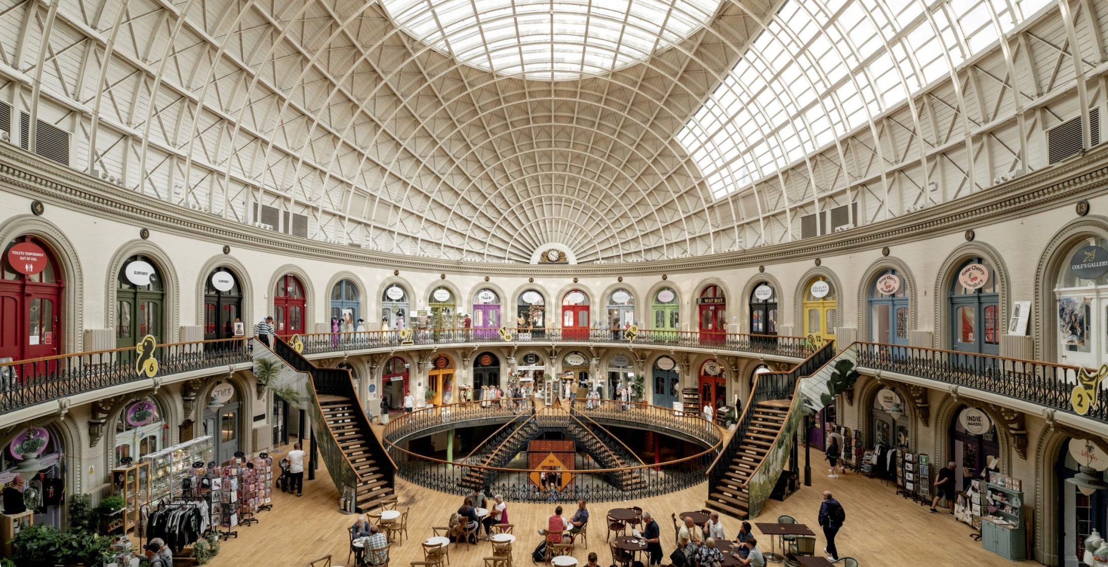 Photo of the inside of Leeds Corn Exchange – a wide open, circular interior with a domed roof and brightly coloured doors leading off a mezzanine.