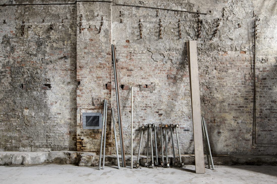 Photo of the inside of the Pattern Shop before work was completed – an old, grey stone building with timber and metal poles leaning against the wall.