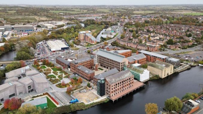 Aerial photo of an urban development – a mixture of new and heritage buildings – built alongside a river.